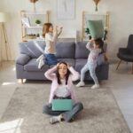 Mamá multitarea en sala de estar mientras cuida a sus hijos y organiza pendientes