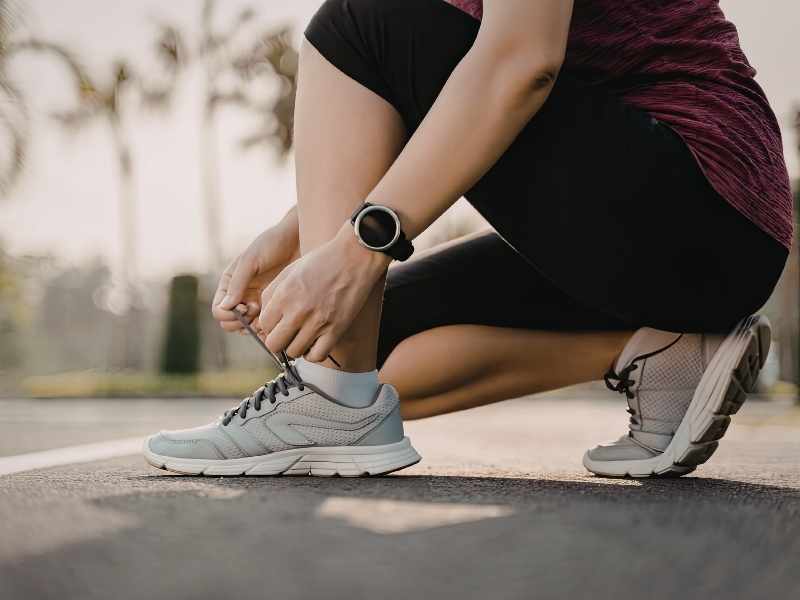 Persona amarrándose los tenis antes de comenzar un nuevo reto deportivo al aire libre